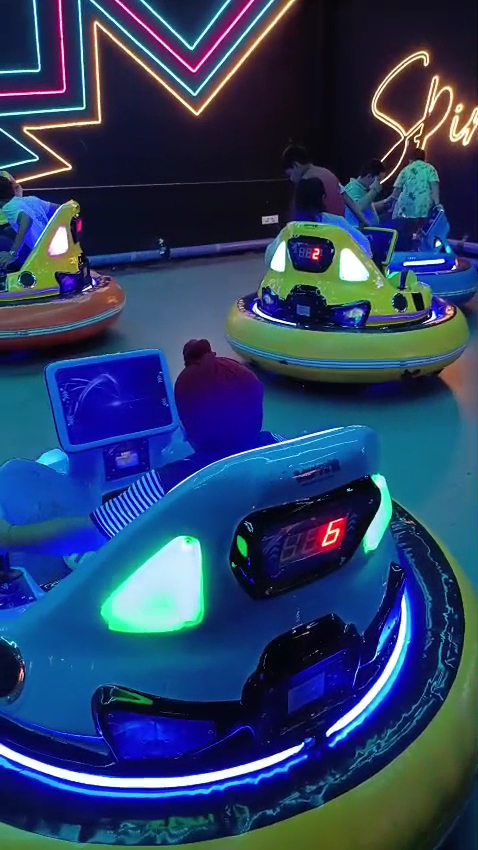Kids steering bumper cars on the neon track