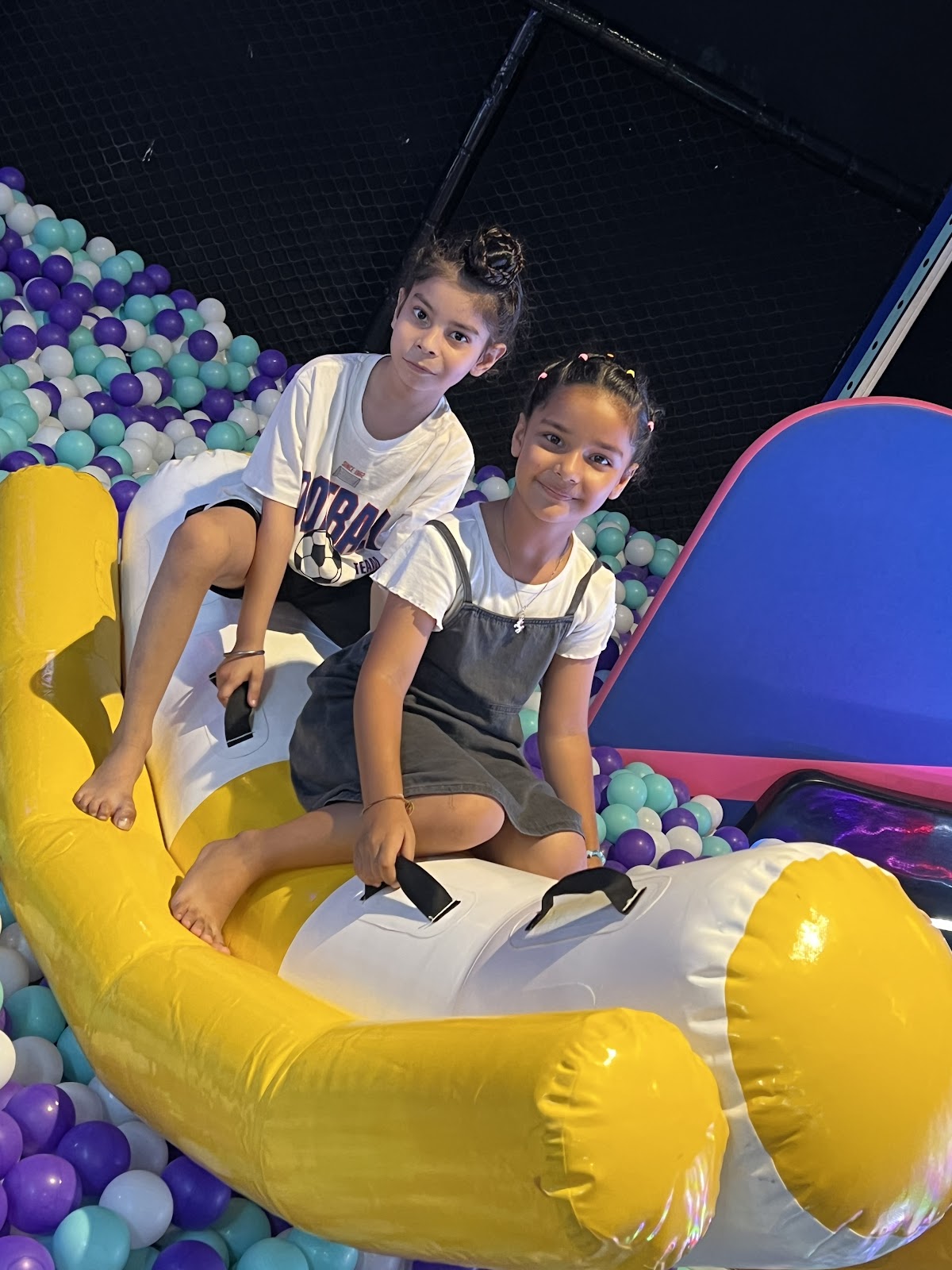 Kids enjoying inflatable banana rocker in ball pit